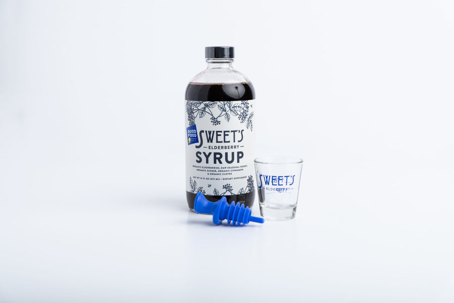 Sweet's Starter Pack includes a 16 oz family-size bottle of organic Elderberry Syrup, a blue lidded reusable spout, and a dosage-marked shot glass bearing the Sweet's logo.