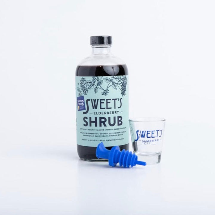 Sweet's Cocktail Collection includes a 16 oz bottle of award-winning organic Elderberry Shrub, a blue lidded reusable spout, and a measurement-marked shot glass bearing the Sweet's logo.